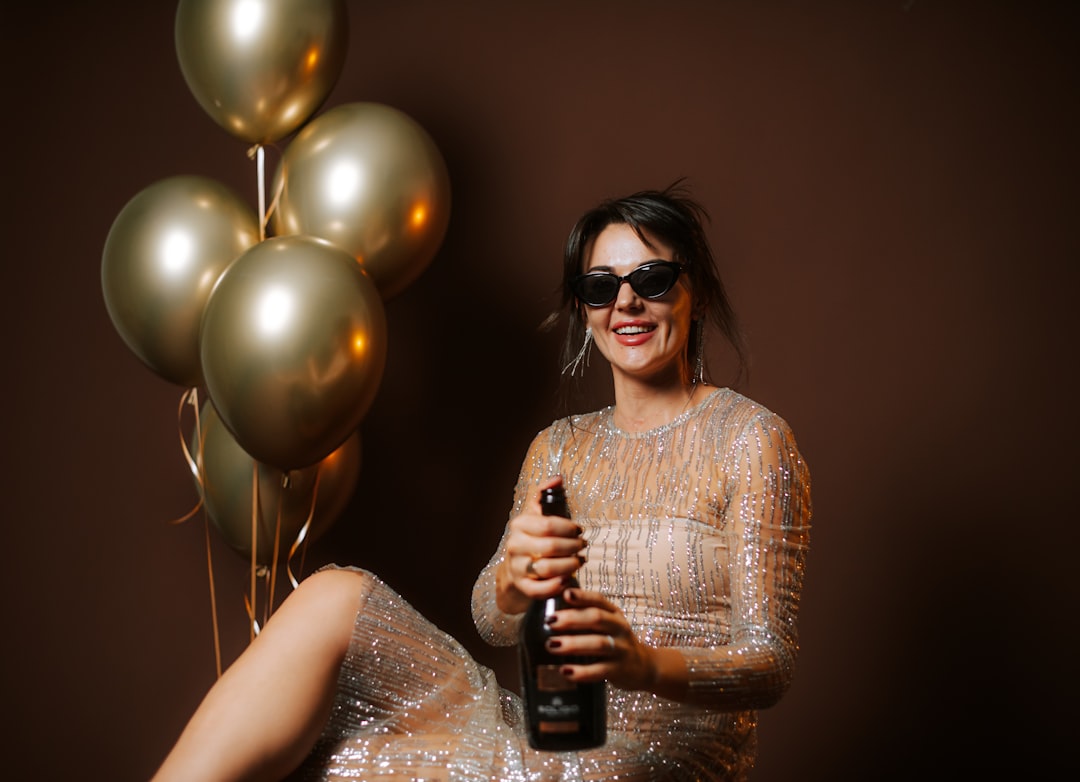 Woman in a sparkly dress celebrating her 50th birthday with champagne and balloons