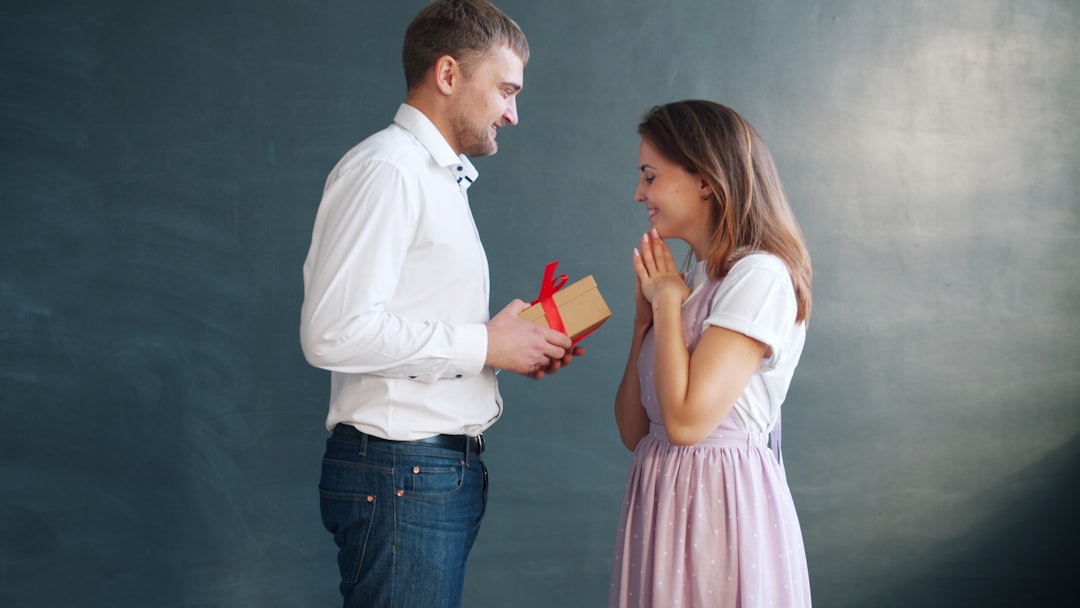 Boyfriend giving a wrapped birthday gift box to his excited girlfriend