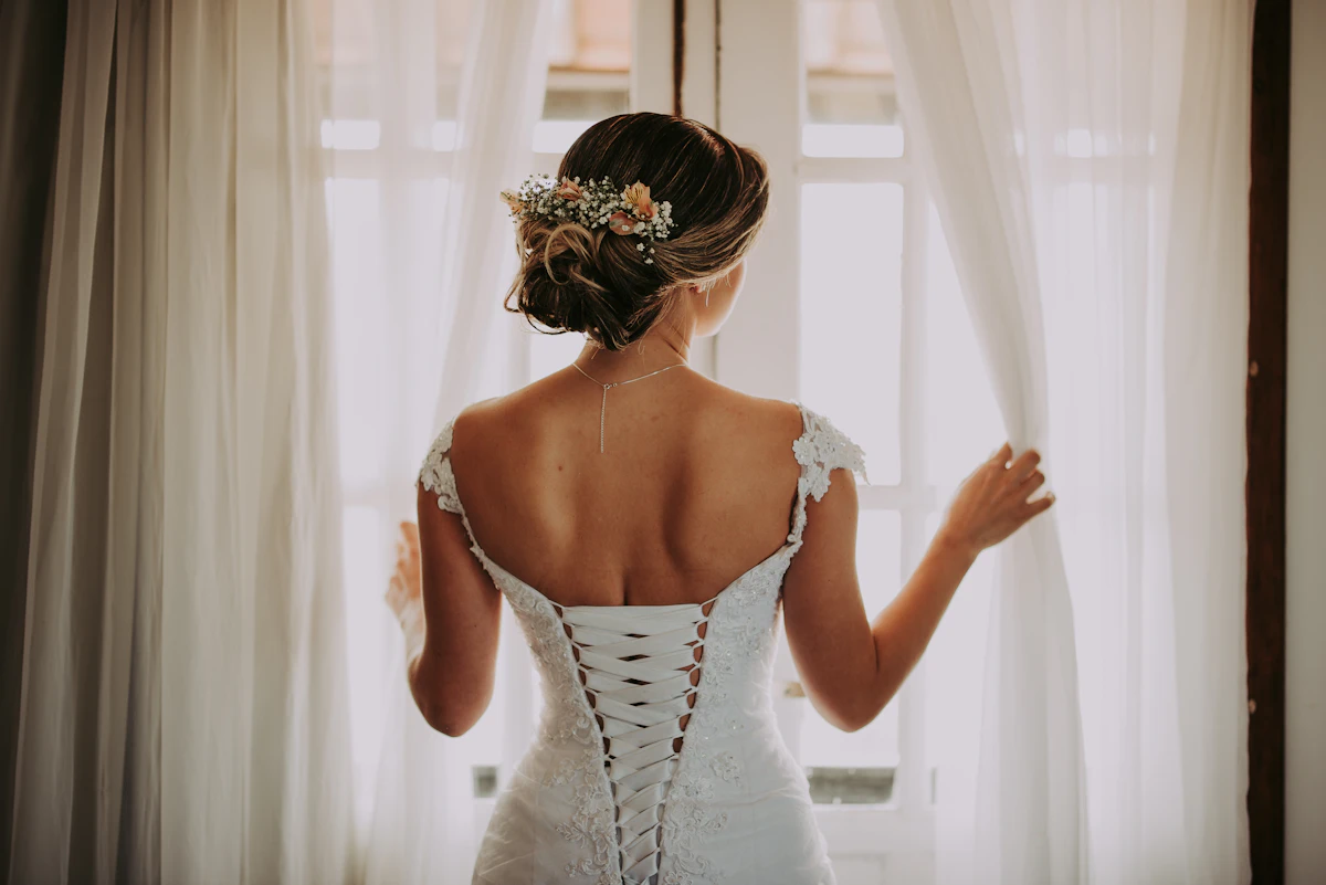 Bride in a fit-and-flare wedding dress standing by a window