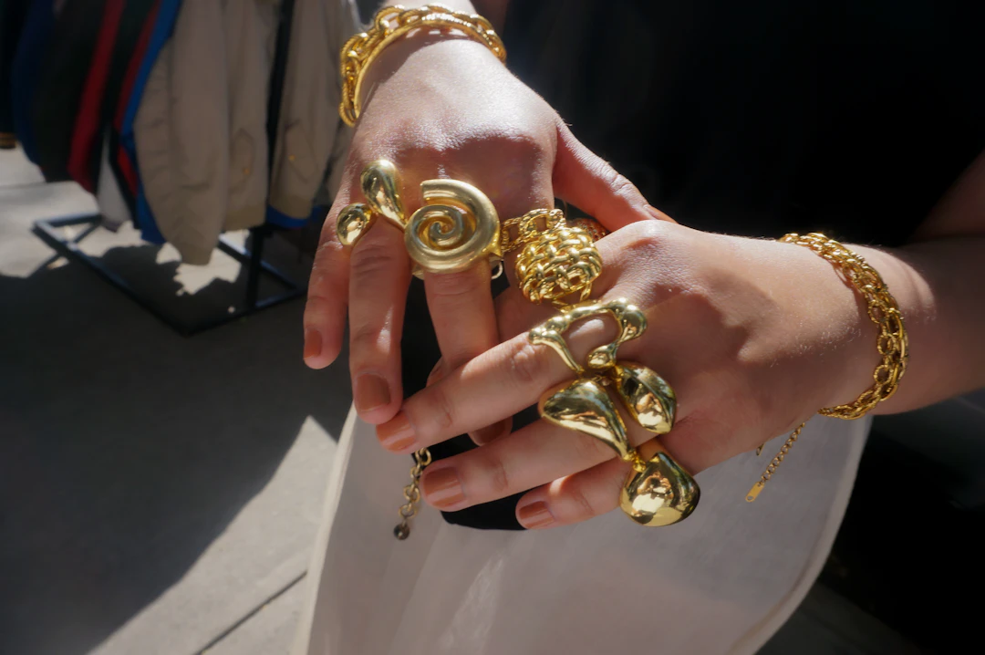 Hands adorned with chunky gold rings and bracelets — bold gold stacks for Leo women