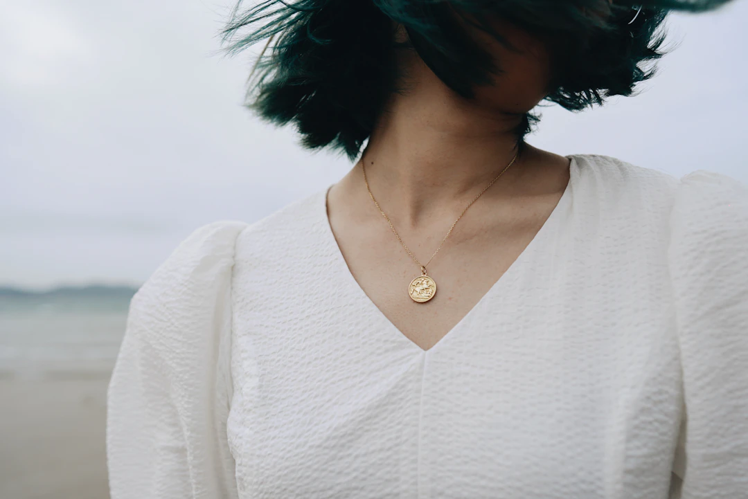Woman in a white v-neck wearing a dainty pendant necklace — refined everyday jewelry for Virgo