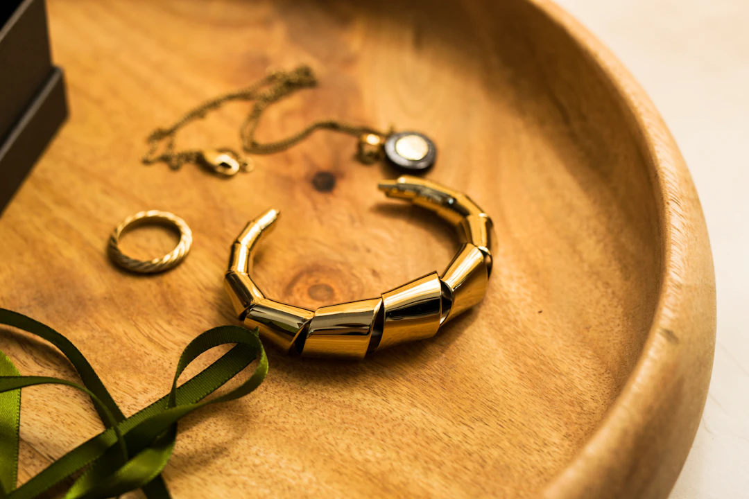 Collection of bold gold jewelry on a wooden tray — warm yellow gold suits Leo women