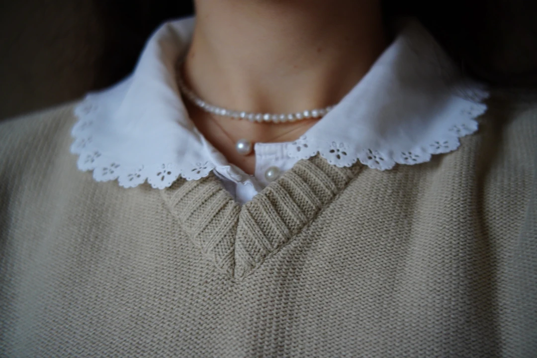 Woman in a soft sweater wearing a pearl necklace — dreamy everyday jewelry for Pisces
