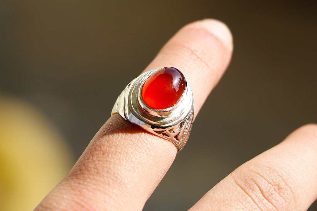 Red gemstone ring on a hand, a carnelian-style love talisman for Aries