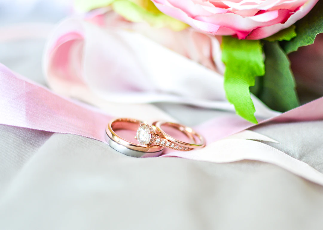 Silver and gold rings beside a pink flower — romantic Venus-ruled style for Libra women