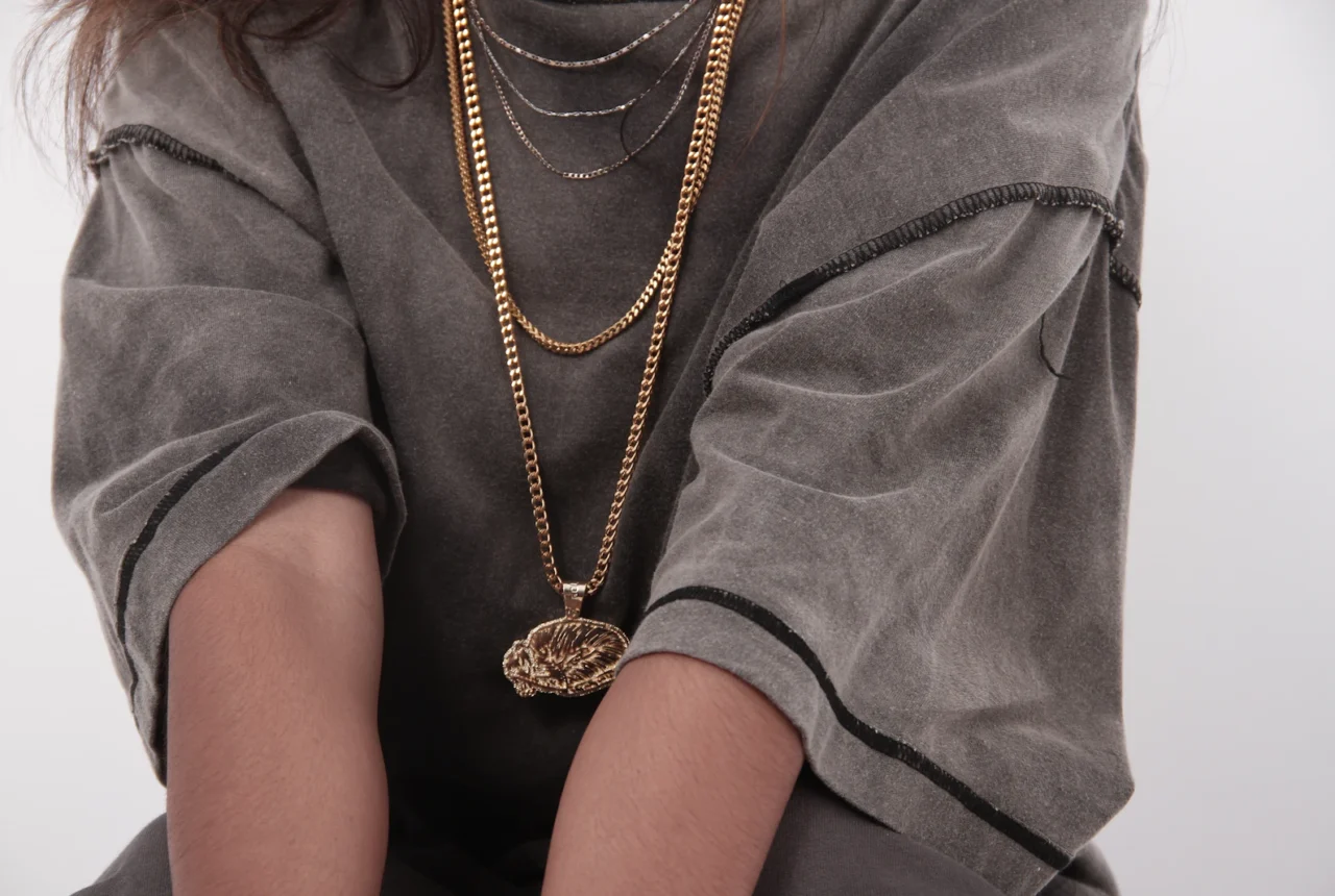 Layered gold chain necklaces worn at staggered lengths