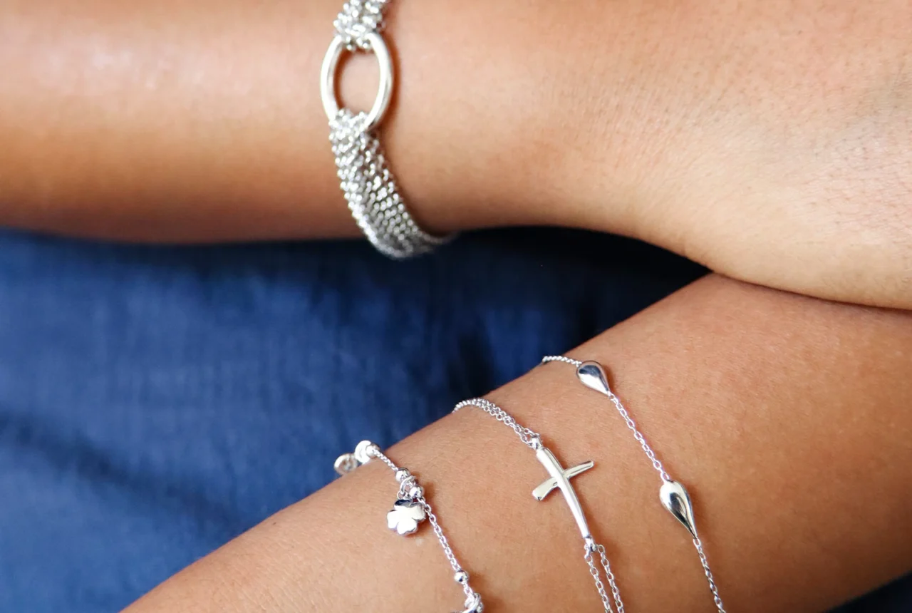 Woman wearing several different styles of silver bracelets stacked on one arm