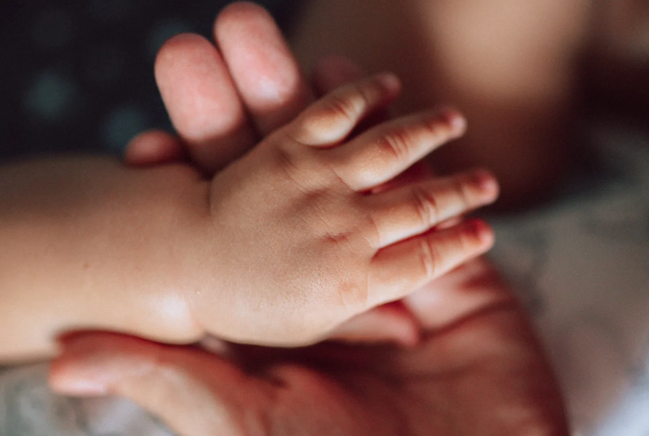 Mother holding her child's hand, a keepsake moment for new mom jewelry