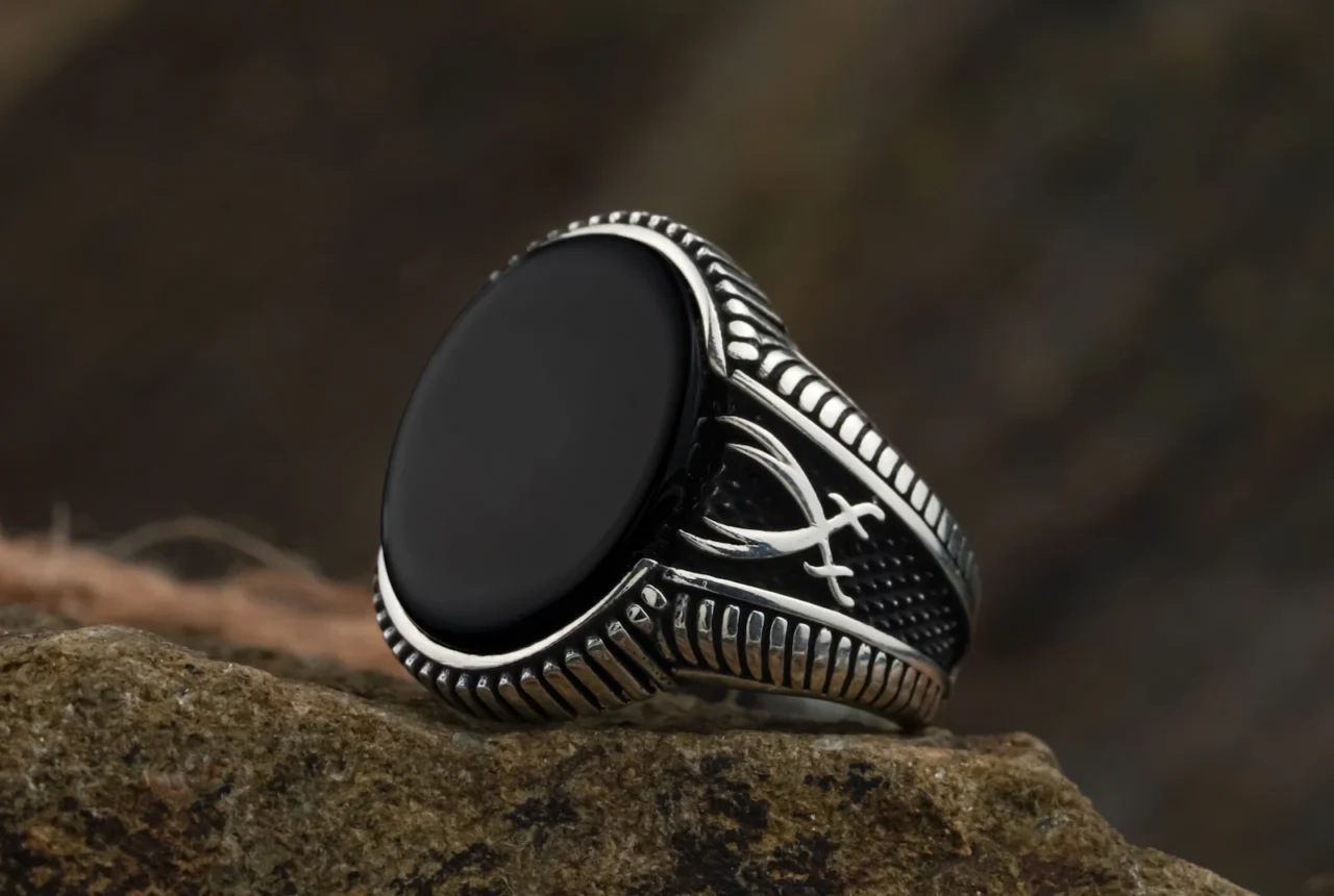 Silver ring set with a black onyx stone resting on rock