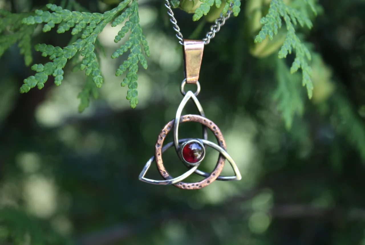 Silver Celtic knot pendant set with a red garnet-colored stone